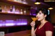 A woman sitting at a bar holding a glass of orange juice.