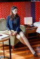 A woman sitting on a chair in a hotel room.