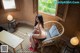 A woman sitting on a chair in front of a window.