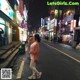 A woman standing in the middle of a city street at night.