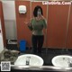 A woman taking a selfie in a public restroom.