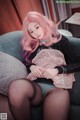 A woman with pink hair sitting on a couch.