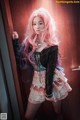 A woman with pink hair standing in front of a door.