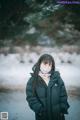 A woman wearing a face mask standing in the snow.