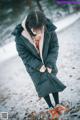 A woman in a black coat is standing in the snow.