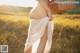 A woman in a white dress holding a basket in a field.