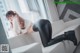 A woman laying on a white couch wearing black leather pants.