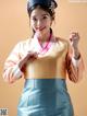 A woman in a blue and orange hanbok is posing for a picture.