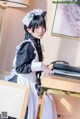 A woman in a maid outfit playing a piano.