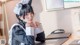 A woman in a maid outfit sitting at a desk.