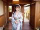 A woman in a blue kimono standing on a wooden floor.