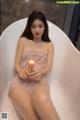 A woman sitting in a bathtub holding a candle.