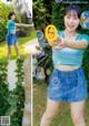 A woman in a blue top and denim skirt holding a soap bubble.