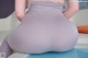 A woman sitting on a yoga mat with her back to the camera.