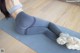 A woman in a gray sports bra top and gray leggings laying on a yoga mat.