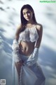 A woman in a white lingerie posing in the snow.