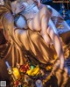 A woman laying on top of a bed next to a bowl of fruit.