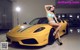 A woman in a bikini sitting on a yellow sports car.