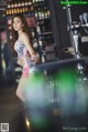 A woman standing in front of a bar with a beer tap.