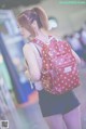 A woman with a red backpack is walking through an airport.