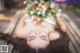 A woman laying on a wooden bench with a flower crown on her head.