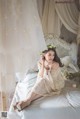 A woman sitting on a bed with a flower crown on her head.