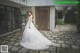 A woman in a wedding dress standing in front of a building.