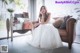 A woman in a wedding dress sitting on a couch.