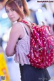 A woman with a red backpack is standing in an airport.