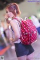 A woman with a red backpack talking on a cell phone.