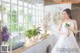 A woman in a wedding dress standing in front of a window.