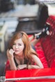 A woman sitting in the back of a red car.