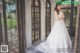 A woman in a wedding dress standing in front of a window.