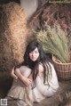 A woman sitting on the ground next to a pile of hay.