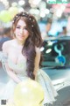 A woman in a white dress holding a bunch of yellow balloons.