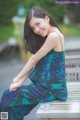 A woman sitting on a wooden bench smiling at the camera.