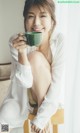 A woman sitting on a chair holding a cup of coffee.