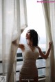 A woman in a white lingerie standing by a window.