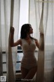 A woman in a white lingerie standing by a window.