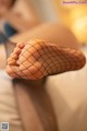 A woman in fishnet stockings is sitting on a bed.