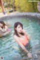 A woman in a pink bikini sitting in a pool.