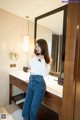 A woman standing in front of a mirror in a bathroom.