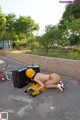 A woman laying on the ground next to a suitcase.