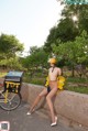 A woman in a yellow jacket and helmet leaning against a wall.