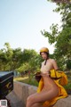 A woman in a yellow raincoat is sitting on a wall.