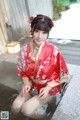 A woman in a red kimono sitting in a bathtub.