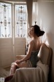 A woman sitting on a chair in front of a window.