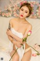 A woman in a white lingerie holding a pink rose.