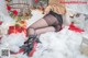 A woman in black stockings and high heels sitting on a pile of snow.