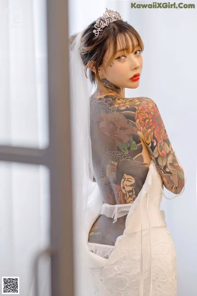 A woman in a wedding dress with a tattoo on her back.